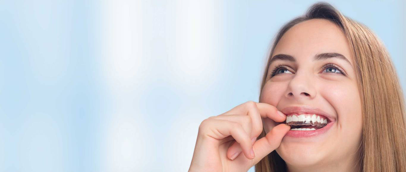 The image features a young woman with a joyful expression, looking upwards and slightly to her left, while holding a green apple close to her mouth. She appears to be about to take a bite of the apple.